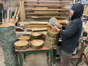 Artist Anthony May inspecting arrangement of cut log rounds for Price Sculpture Forest installation