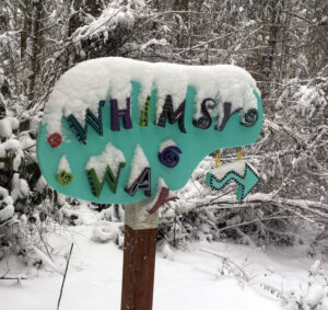 Whimsy Way trail sign by Linda Hauser covered in snow at Price Sculpture Forest park garden Coupeville Whidbey Island