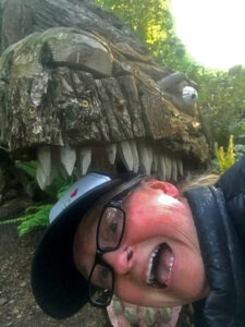 Volunteer Christina Whiting with Joe Treat's Tyrannosaurus Rex at Price Sculpture Forest park garden in Coupeville on Whidbey Island
