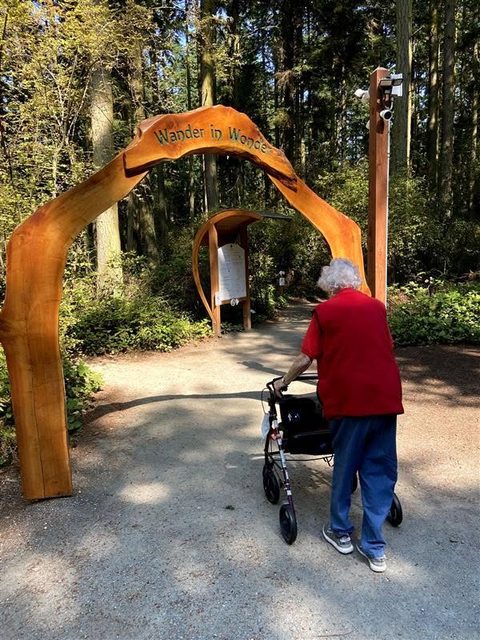 A visitor using a walker beneath the Wander in Wonder entrance arch