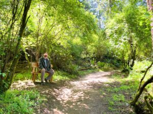 A visitor seated beside a forest trail