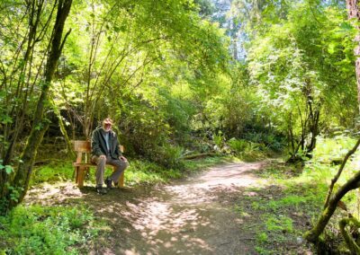 A visitor seated beside a forest trail