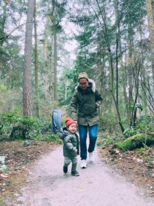 An adult and child walking together on a forest trail