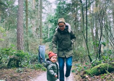An adult and child walking together on a forest trail