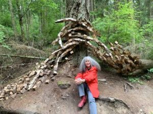 A visitor resting near a natural forest sculpture