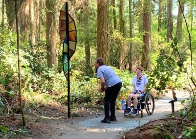 A companion supporting a wheelchair user on the forest trail