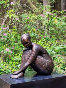 An outdoor figurative sculpture surrounded by forest plants